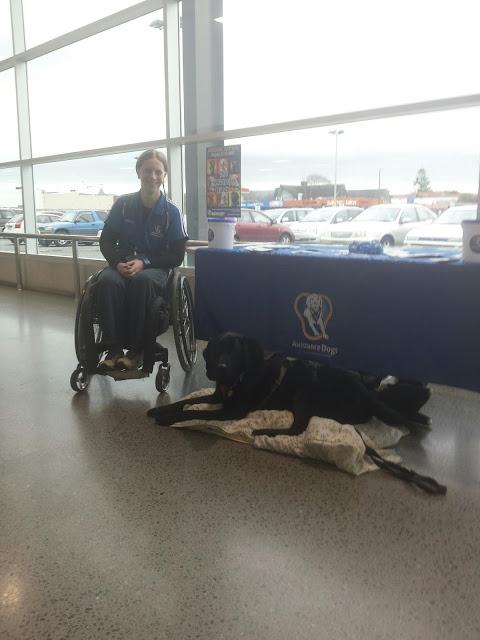 Antnz on left in wheelchair, ADNZ Ben lying on a blanket in front of an ADNZ display table
