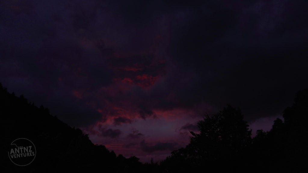 A silhouette of a valley meeting. The rest of the picture is cloud being slightly lit by the first pink rays of sunrise