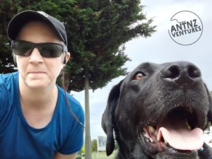  A selfie with Antnz on left, wearing a blue t-shirt, sunglasses and black cap. On right is ADNZ Raven looking beyond the camera, wither her mouth open panting
